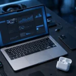 Desk with laptop showing tech website, smartphone and smartwatch.